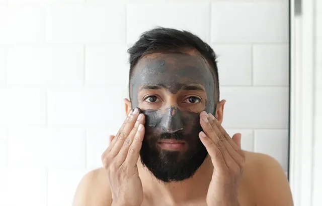 man applying charcoal face mask